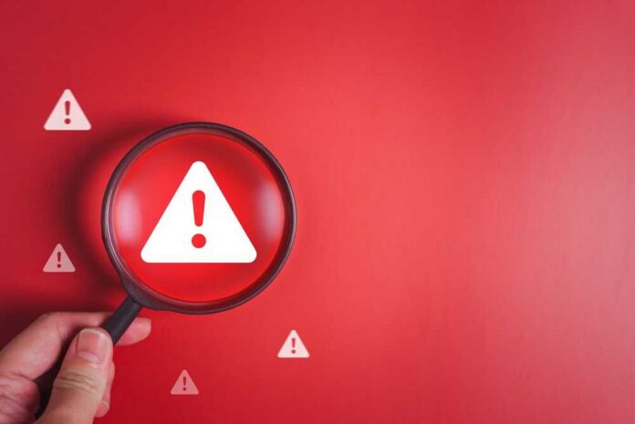 Magnifying glass over a warning triangle on a red background