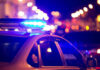 Homecoming Horror Erupts Police car with flashing blue lights at night.